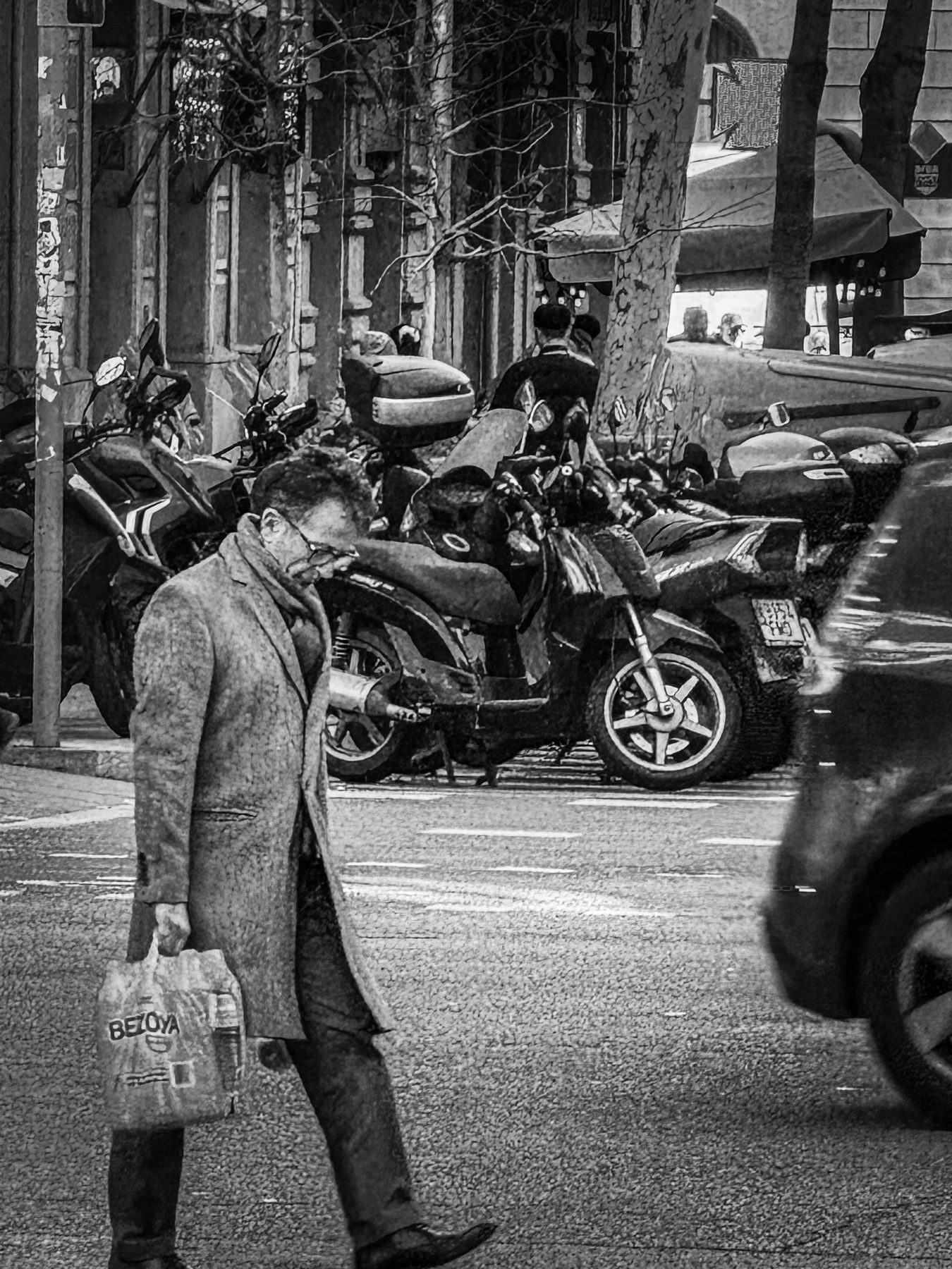 Dos litros — hombre con abrigo largo cruzando la calzada con una garrafa de agua en la mano, junto a una fila de motos aparcadas, en blanco y negro