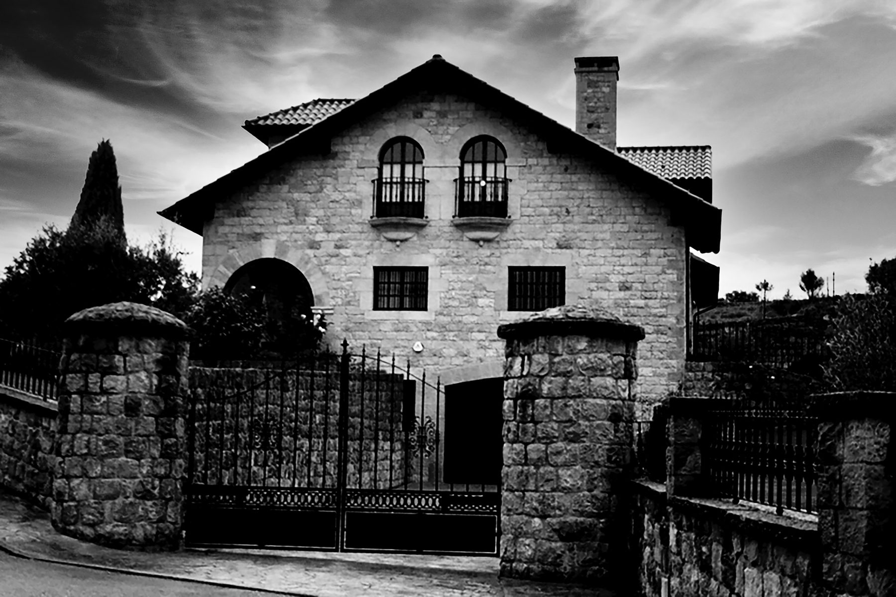 Casa en Santillana del mar — fachada de piedra con verja de hierro, en blanco y negro