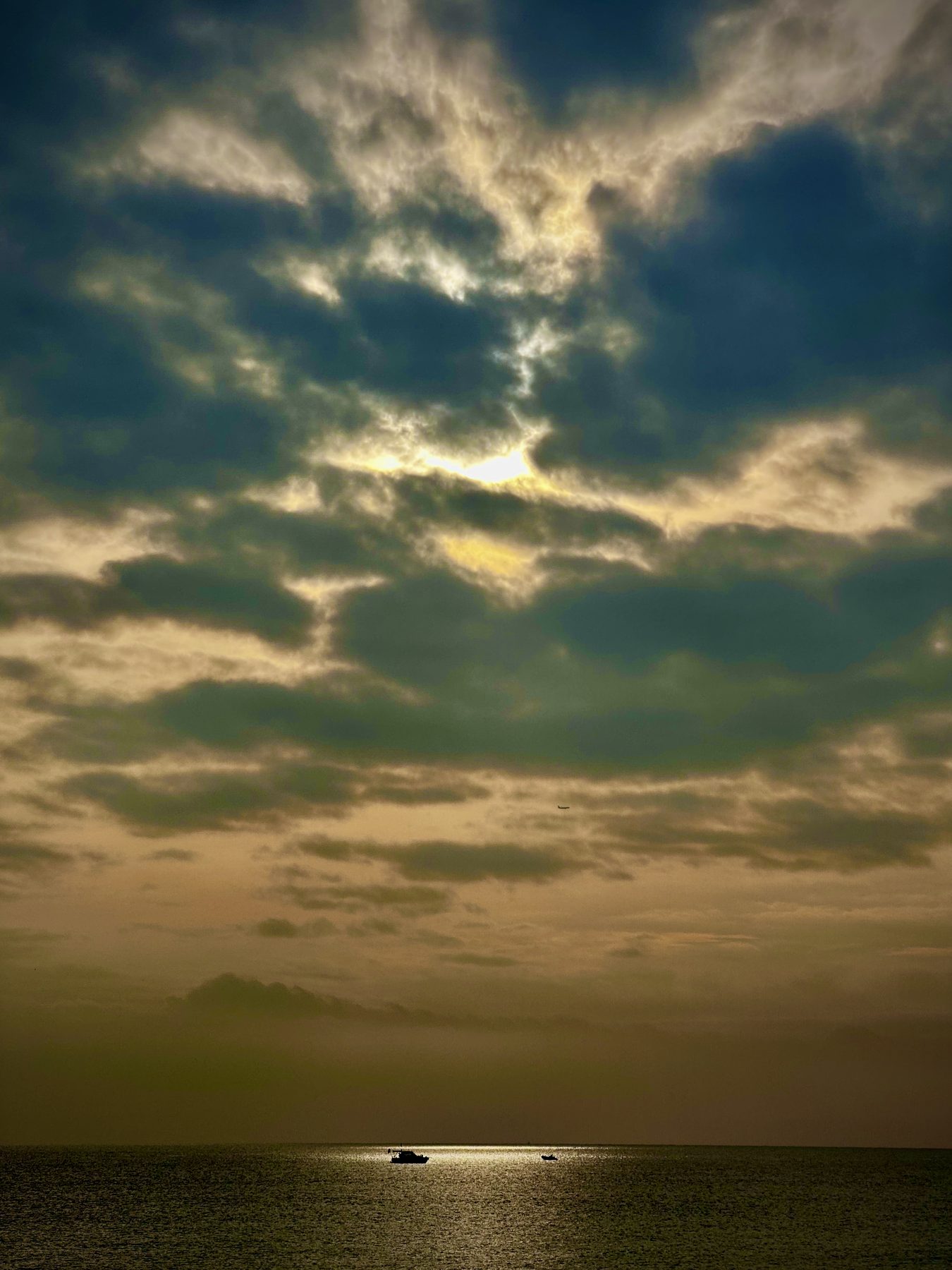Indeciso — Cielo con nubes oscuras y luz verdosa y dorada sobre el mar