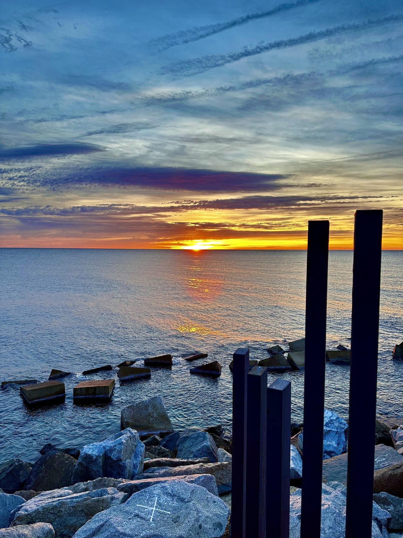 Hierro azul — Postes de hierro azul entre bloques de hormigón en un espigón, al atardecer