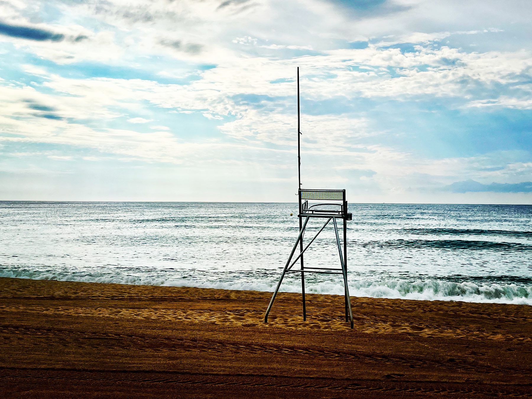 Fuera de temporada — silla de socorrista vacía en una playa desierta frente al mar