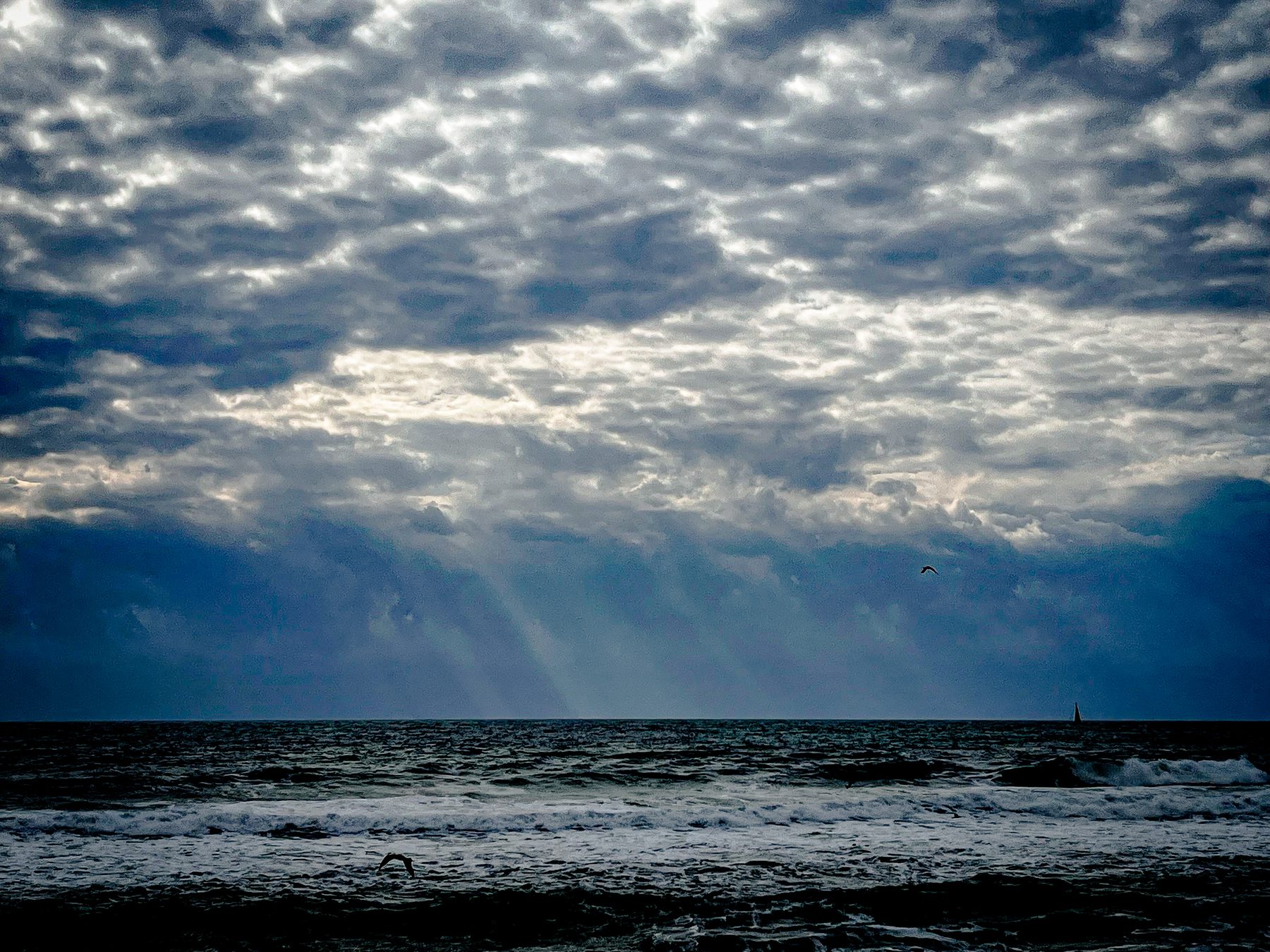 La grieta — Rayos de sol atravesando un manto de nubes sobre el mar