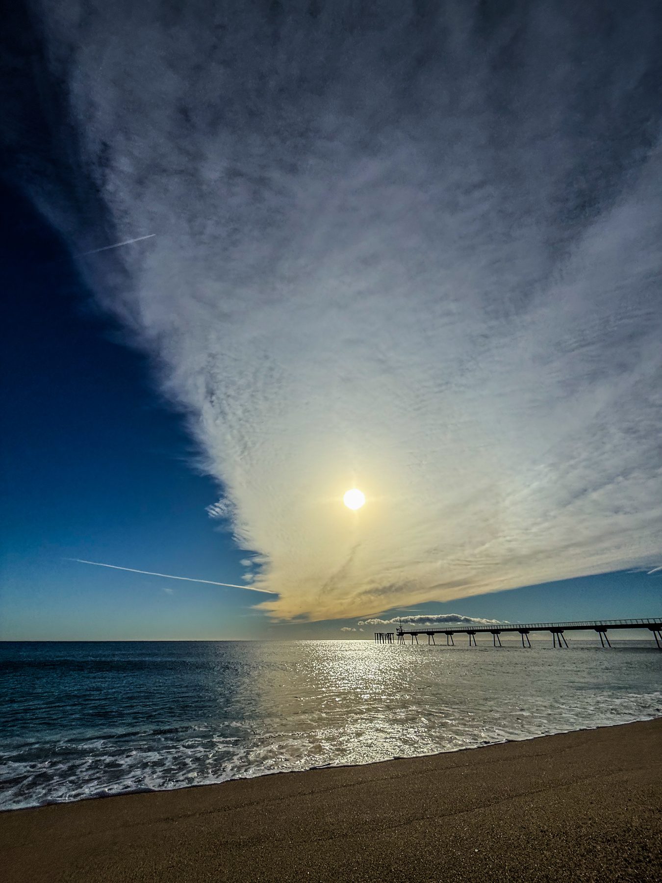 Nube que tapa al sol — el sol se asoma detrás de una gran nube sobre el mar