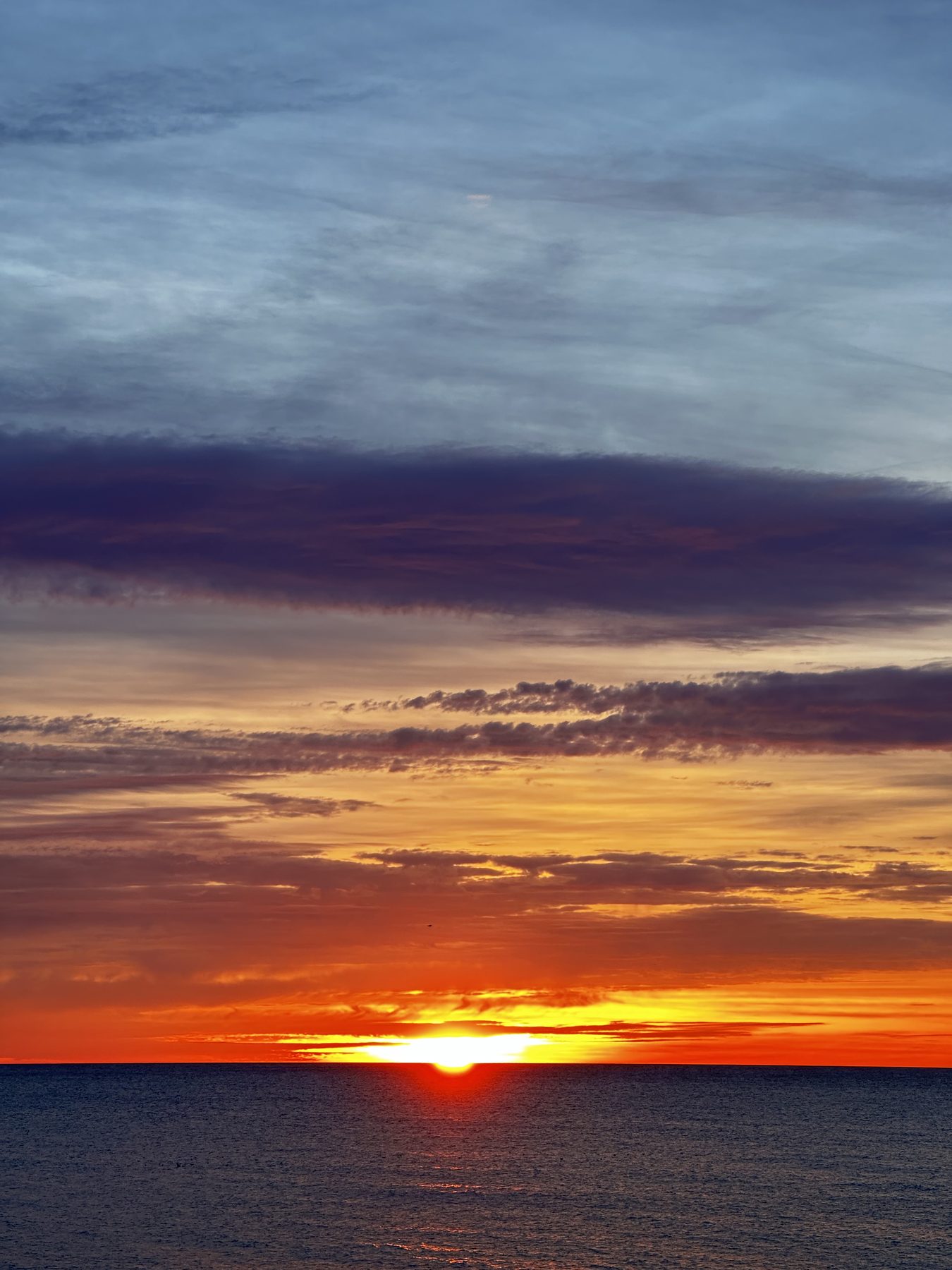 Toca el agua — El sol posado en la línea del horizonte sobre el mar
